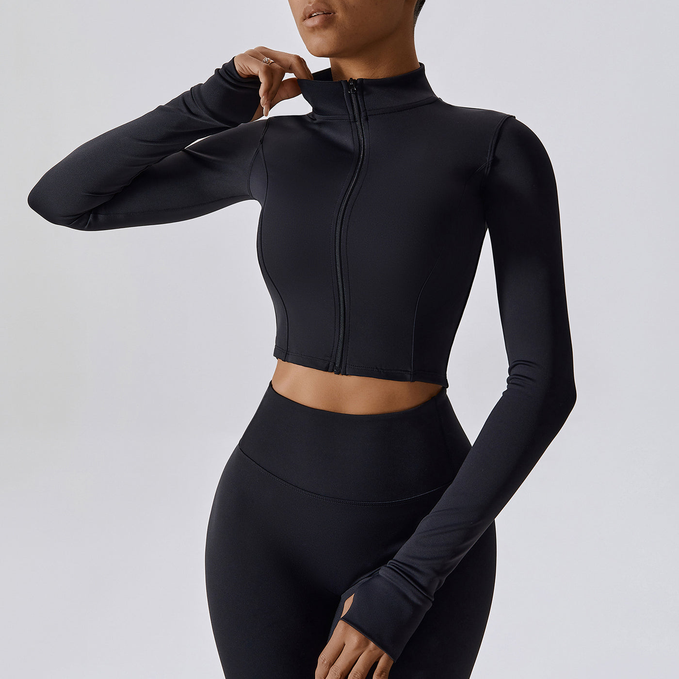 Person wearing a black long-sleeve athletic top and leggings on a light gray background